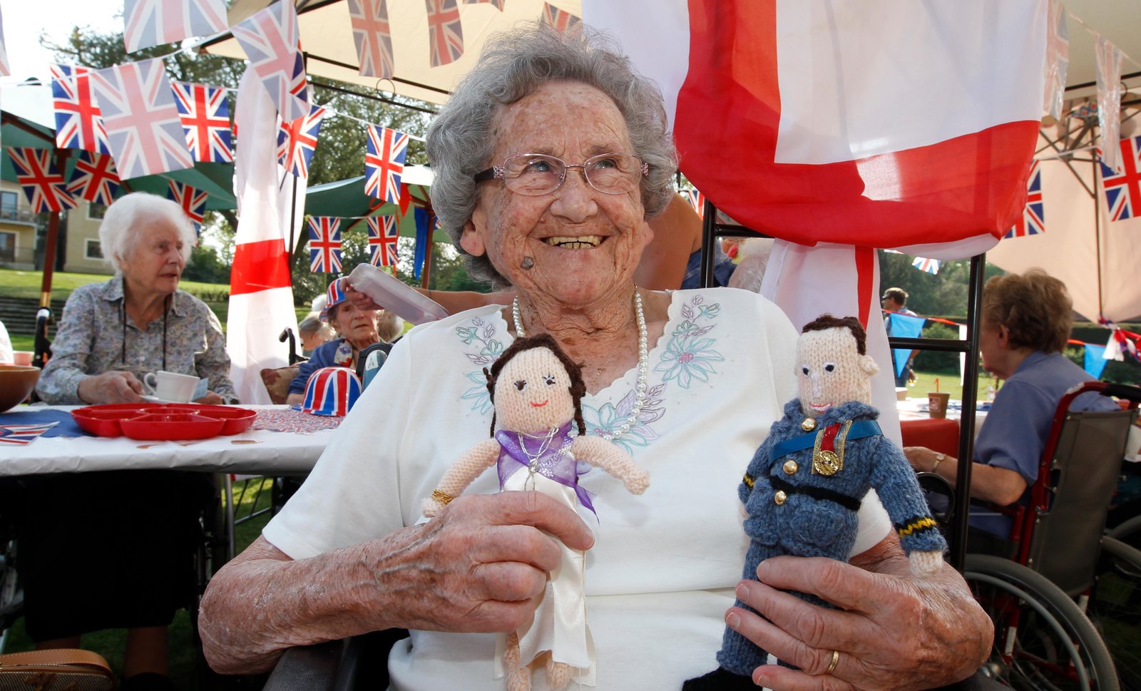 A resident at Abberton Manor holding a knitted doll at a bunting-decked party