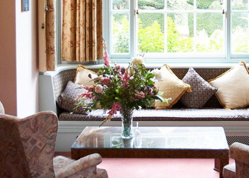 A sitting room at Abberton Manor with a cushioned window seat looking onto the garden
